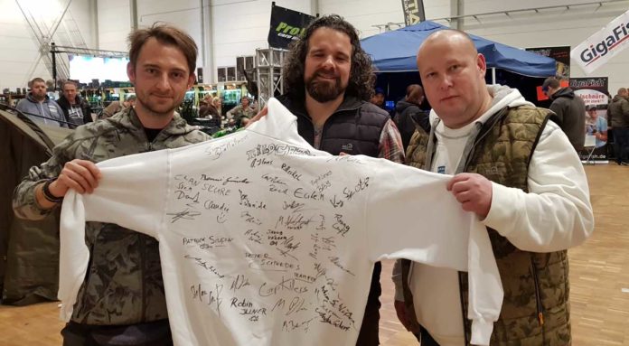 Der Pullover mit den Unterschriften verschiedener Angel-Größen wurde zu Gunsten eines Kinderprojektes versteigert. Von links: Robin Illner, Mark Bergmann und Marcus Sippel-May.