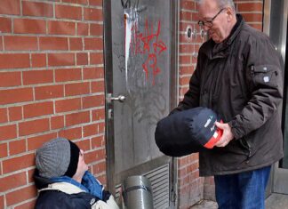 Claus Jonas von der Angelgruppe Hamburg-Harburg überreicht einem Obdachlosen Isomatte und Schlafsack. Foto: St. Maximilian Kolbe Gemeinde