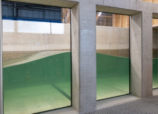 Durch ein großes Unterwasserfenster können die Forscherinnen und Forscher wie bei einem Aquarium in den neuen Wellenkanal schauen. Bild: Kristina Rottig/TU Braunschweig