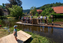 Flößerei-Tradition: Mit einem Floß werden die Gäste des Schiltacher Flößerfests über die Kinzig zur Festwiese gefahren. Bild: TMBW/Andreas Weise