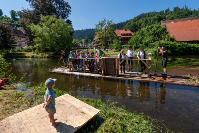 Flößerei-Tradition: Mit einem Floß werden die Gäste des Schiltacher Flößerfests über die Kinzig zur Festwiese gefahren. Bild: TMBW/Andreas Weise